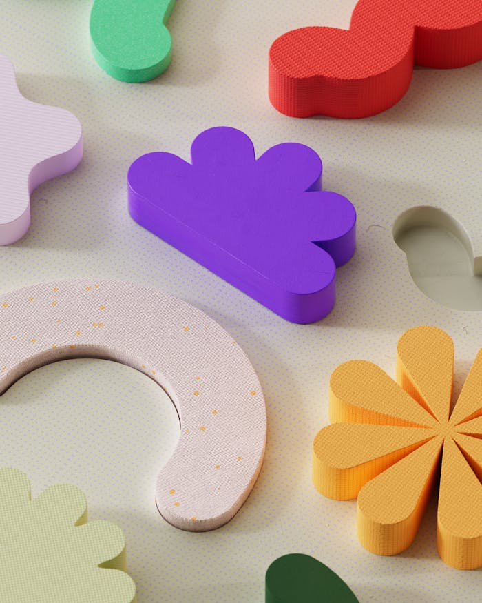 Vibrant assorted abstract 3D shapes arranged in a playful pattern on a light background.